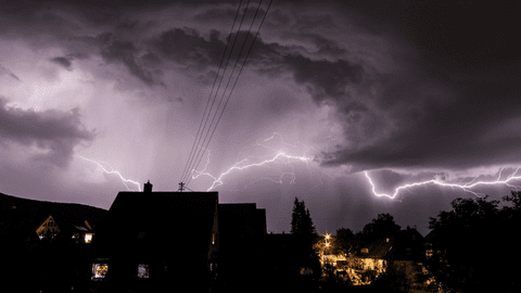 Lightning in clouds over a house at night